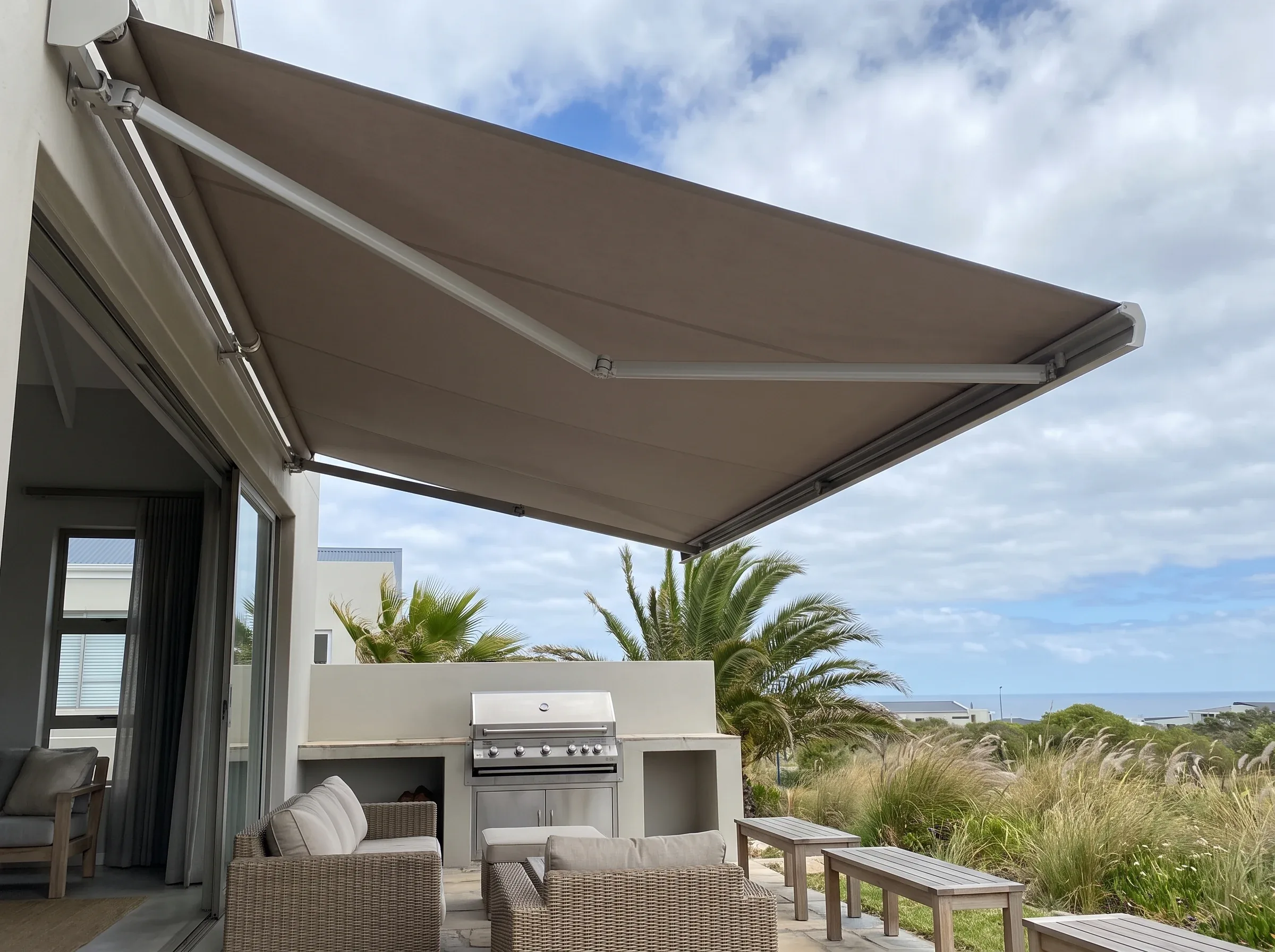 Retractable folding-arm awning shading a Sunningdale braai patio