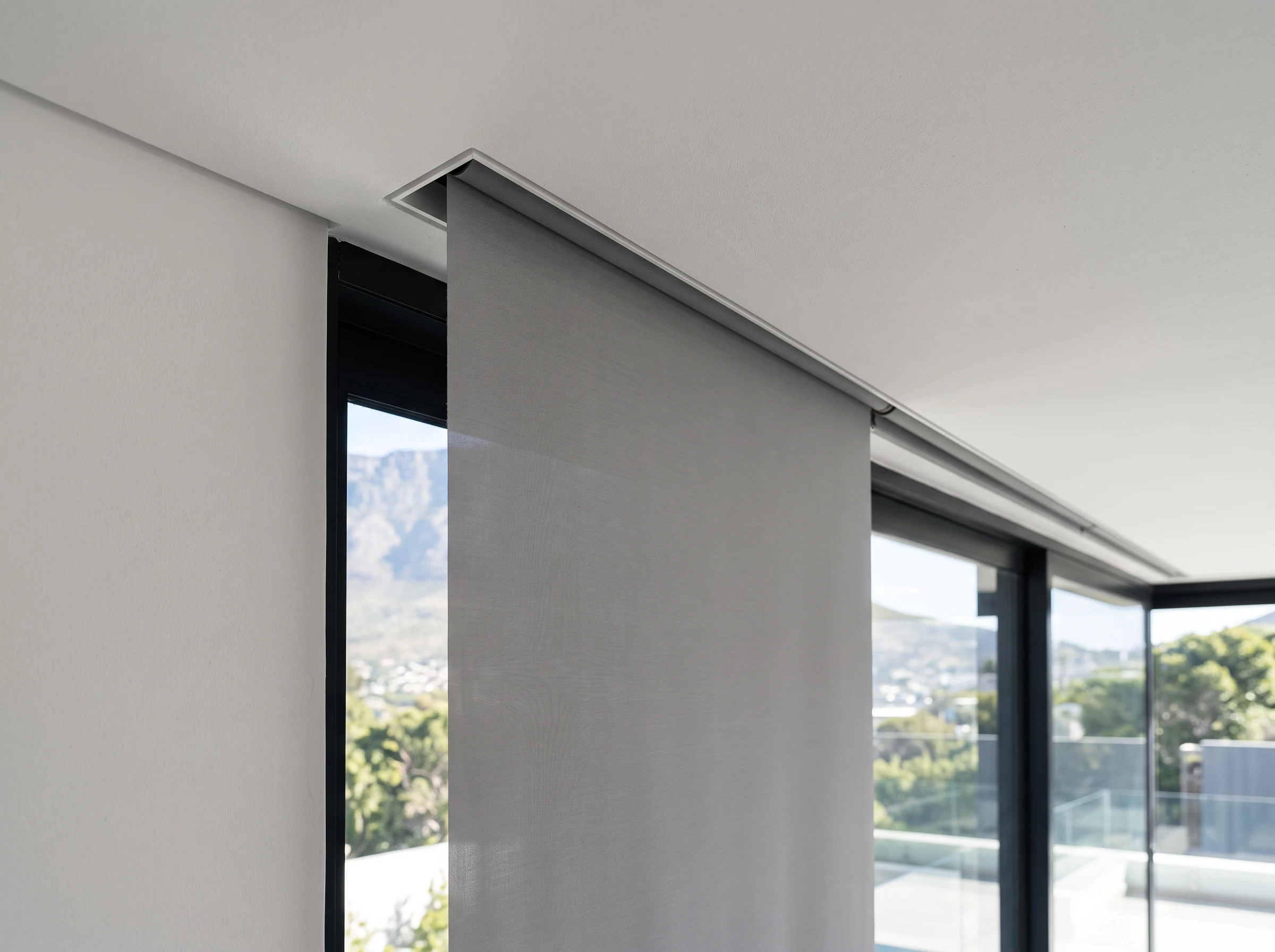 Roller blind fabric emerging from a slim recessed ceiling slot above a window seat in a Sunningdale new-build home